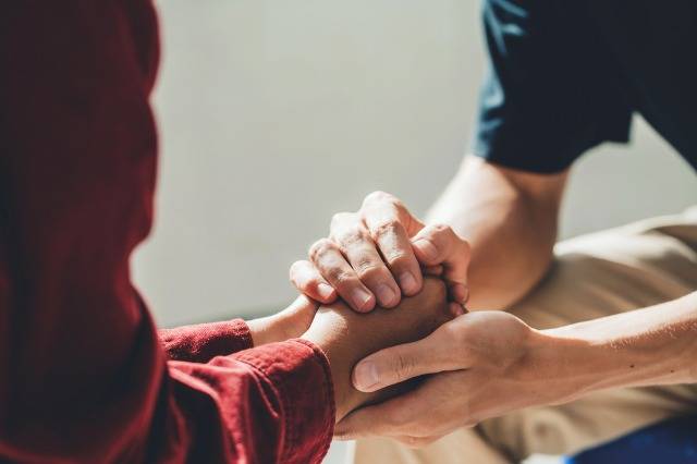 Man holding a woman's hand for warm, as psychological counseling